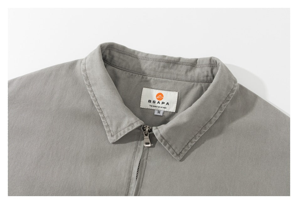 Close-up of a gray jacket's pointed collar, front zipper, and sewn BSAPA neck label.