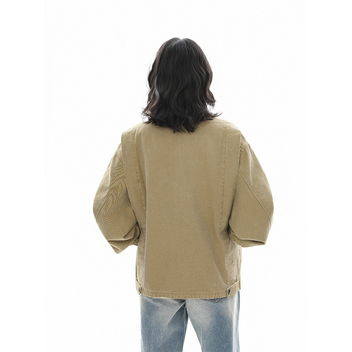 Back view of a model wearing a khaki jacket with roomy sleeves and adjustable tabs at the hem.