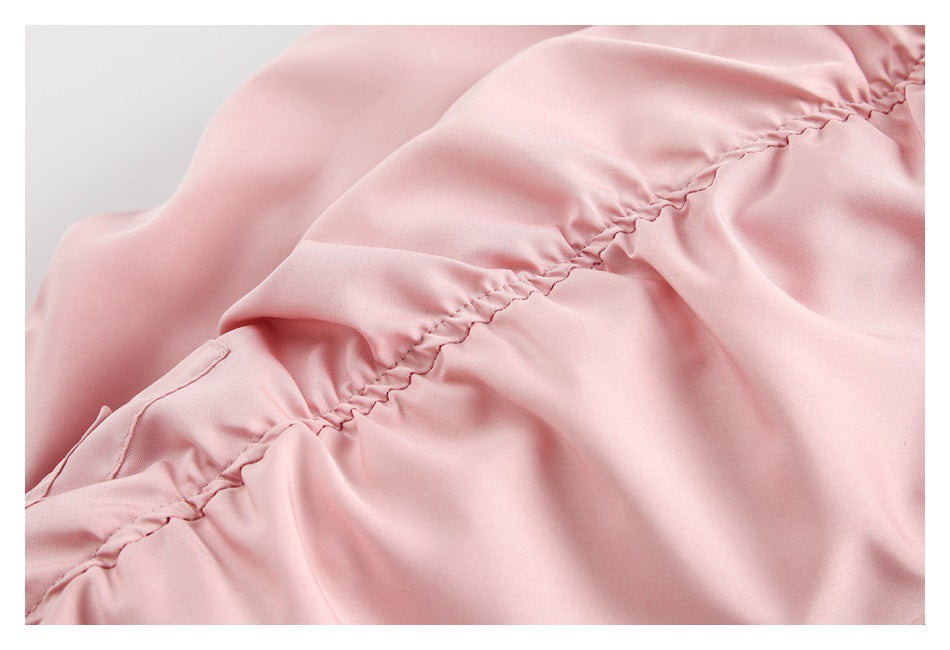 Close-up of a gathered, stitched seam on pale pink jacket fabric.