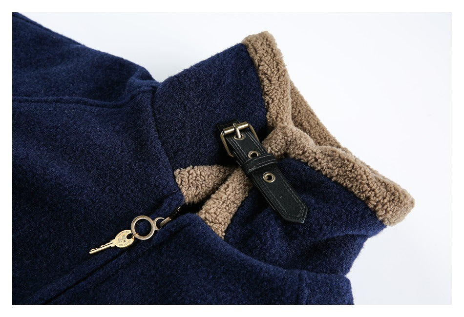 Close-up of a navy jacket collar with tan curly trim, a black buckle strap, and a brass zipper pull.