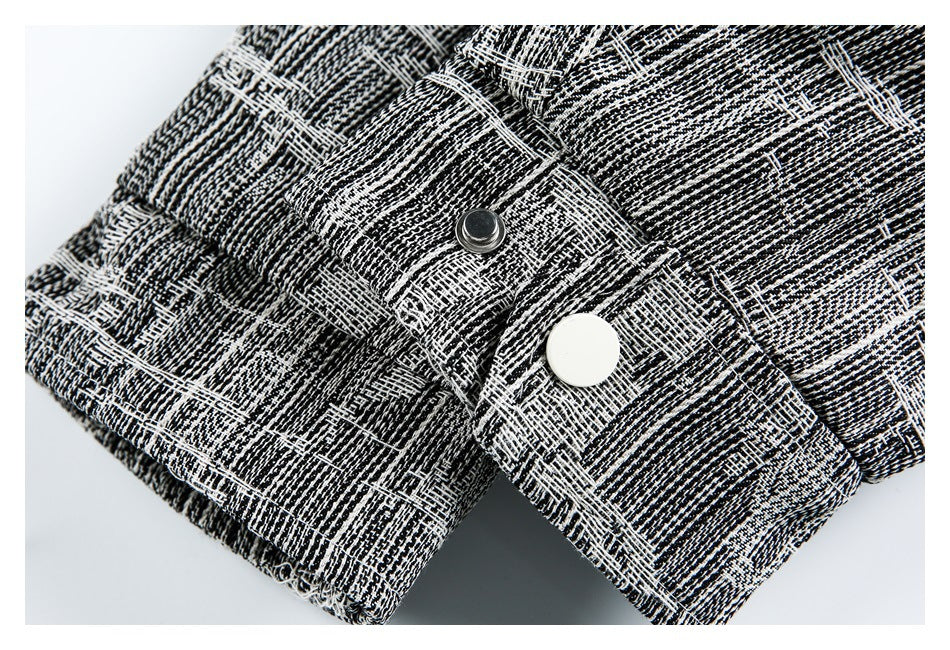 Close-up of a black-and-white patterned garment tab with a metal snap and a white round button.