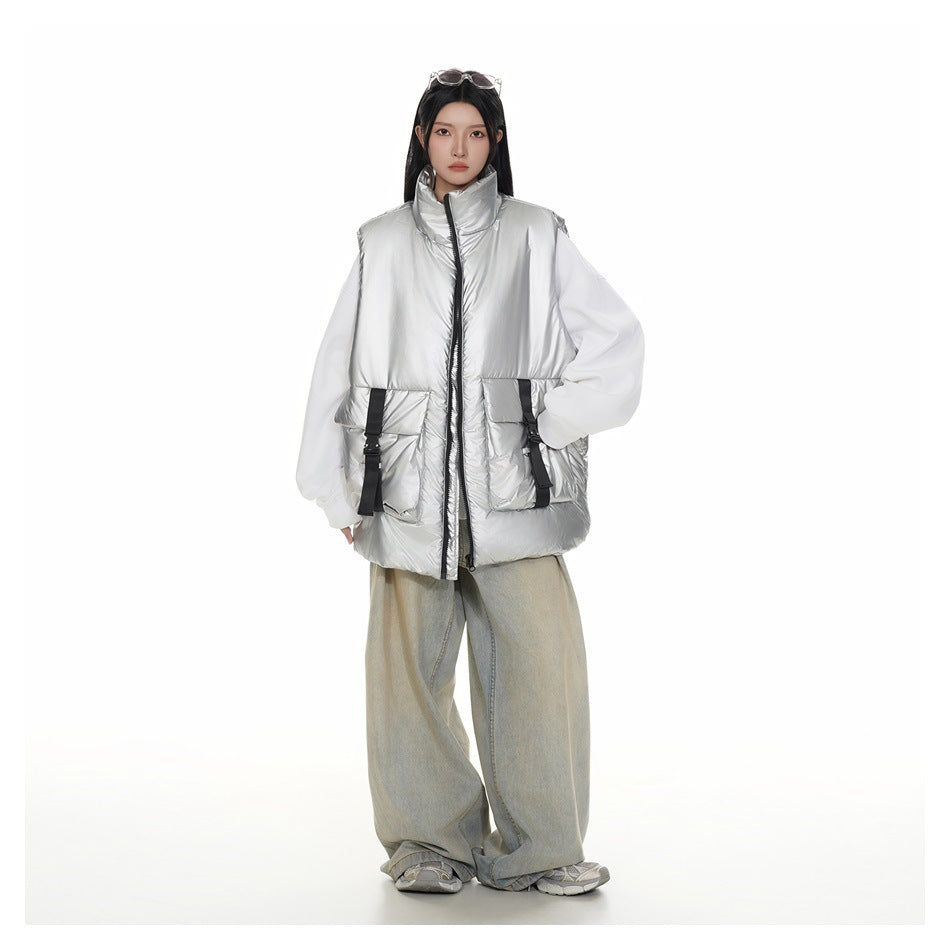 Full-length view of a model wearing a shiny silver padded vest with a high collar, front zip, and large buckle-detail