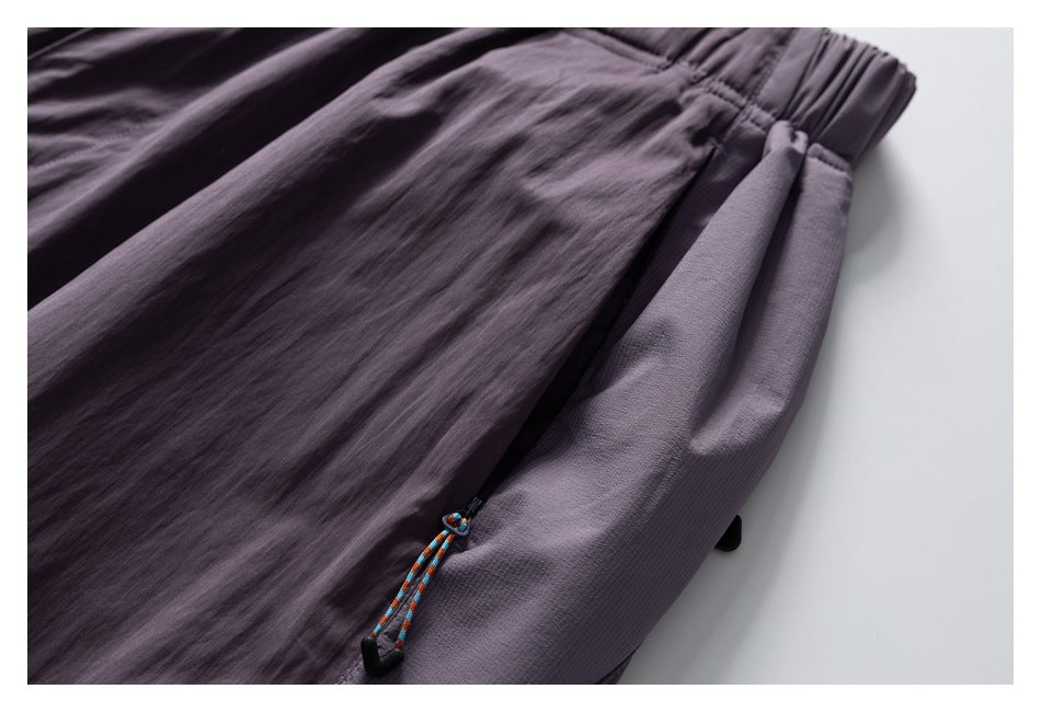 Close-up of mauve-gray pants showing a side pocket and a colorful cord with a black toggle.
