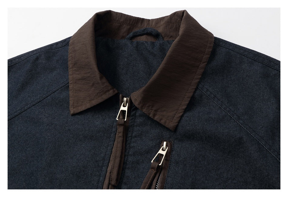 Close-up of a dark indigo jacket's brown collar and front zipper with metal pull.