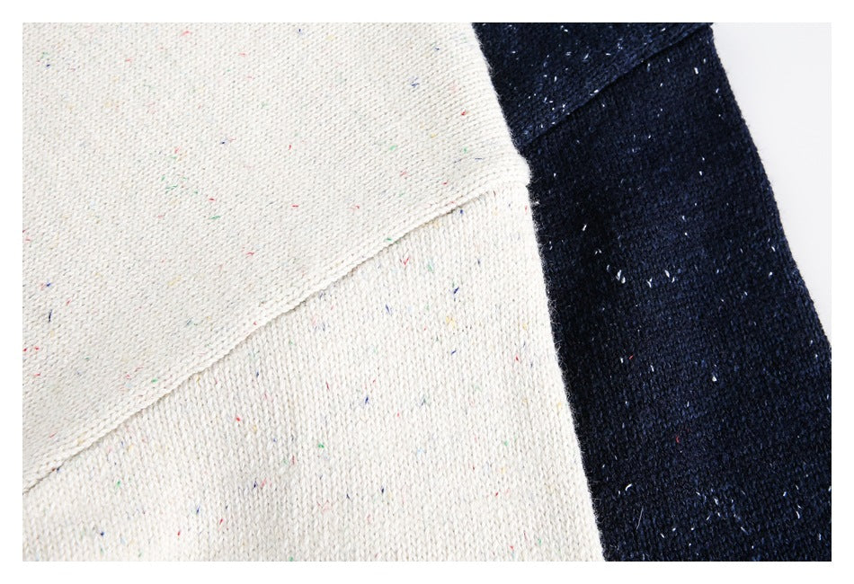 Close-up of cream and navy knit fabric with scattered multicolored flecks.