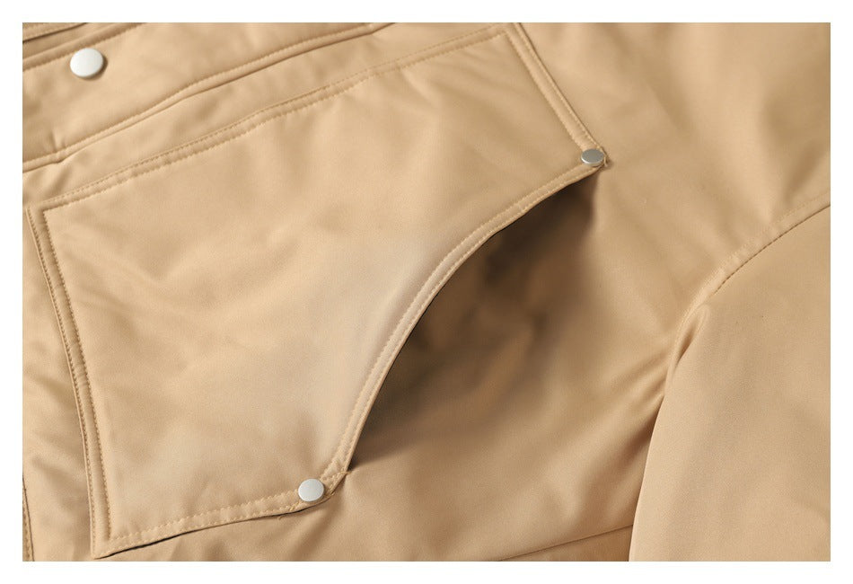 Close-up of a tan jacket pocket with stitched edging and silver snap fasteners.