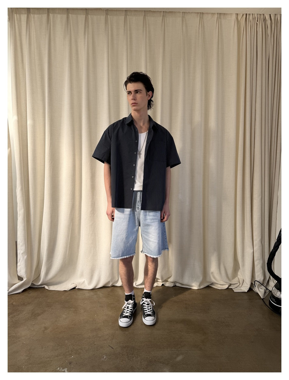Model wearing the striped short-sleeve shirt open over a white tank top with light denim shorts, front view