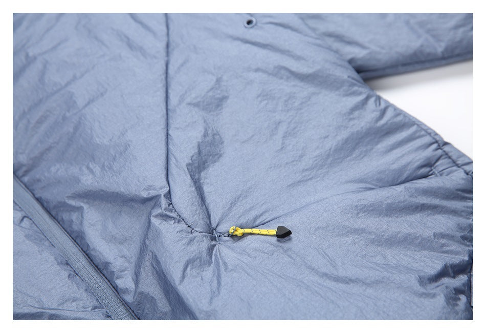 Close-up of blue-gray fabric with a gathered seam, eyelet, and yellow cord toggle.