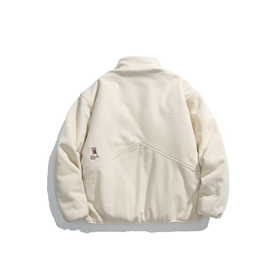 Back view of an ivory pullover with a raised collar, curved seam detail, and small embroidered mark.