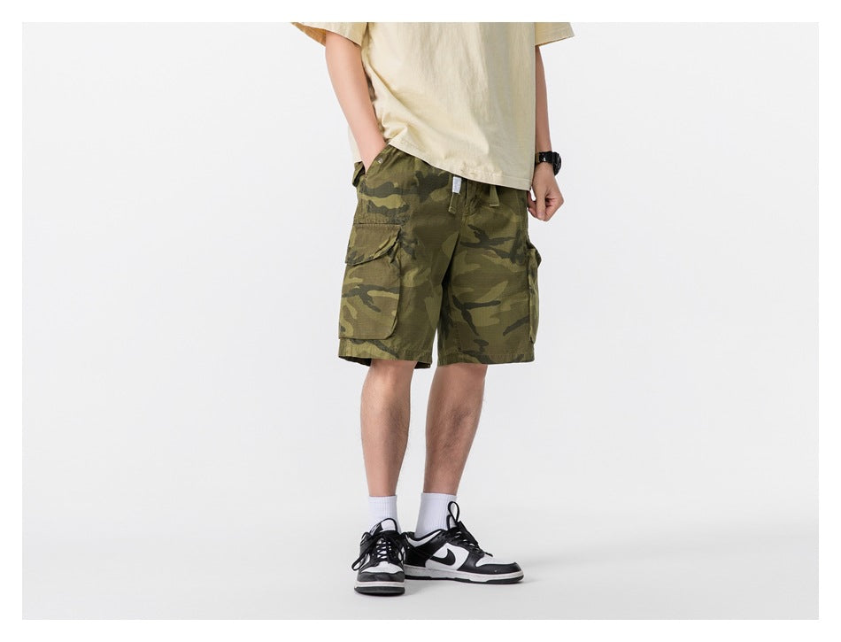 Model wearing olive camouflage cargo shorts, shown from a front three-quarter angle.