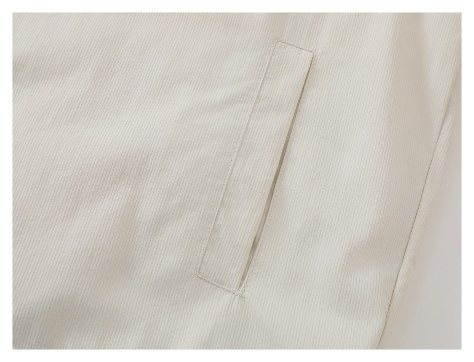 Close-up of a narrow vertical slit pocket on ivory fabric with fine vertical texture.