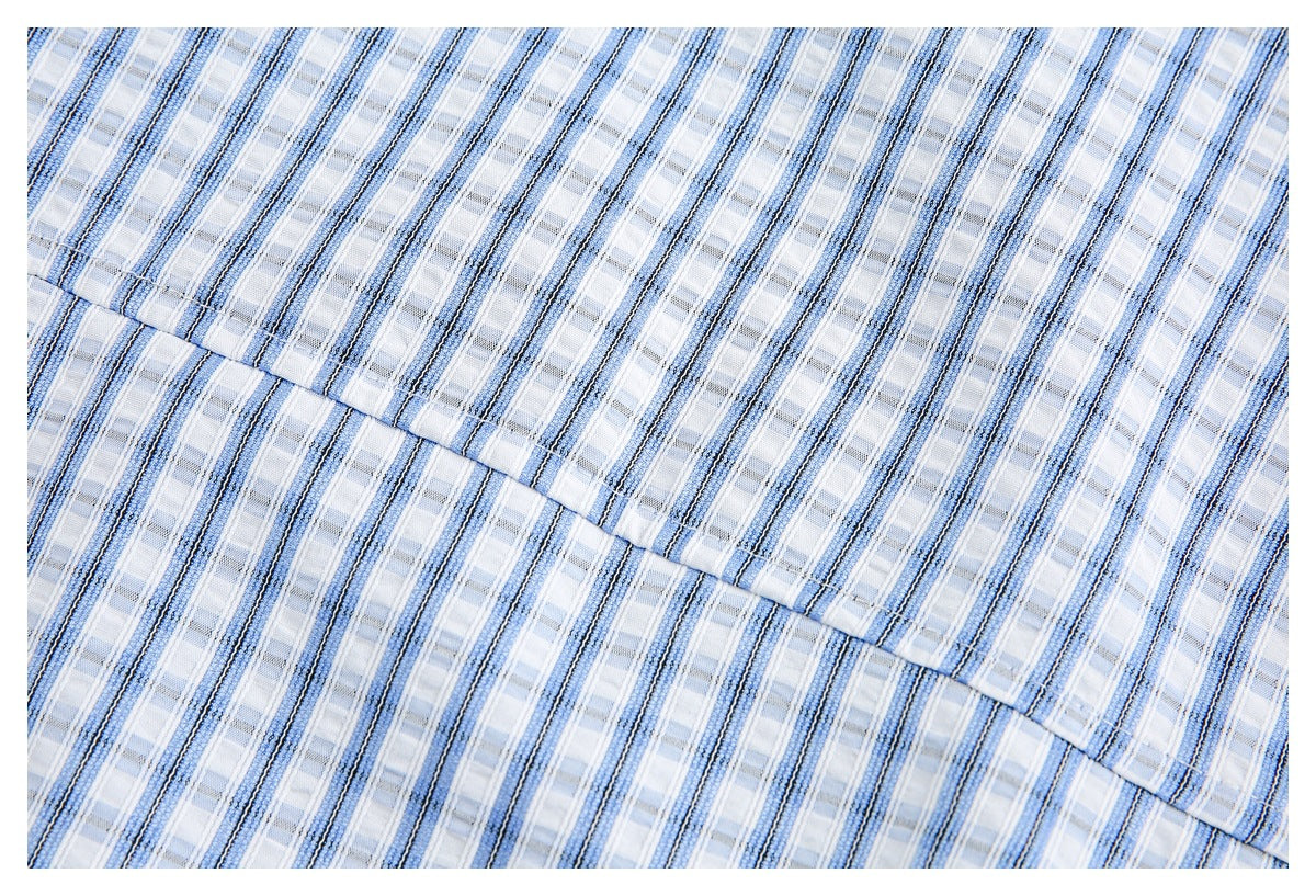 Close-up of white fabric with blue and gray plaid stripes and a diagonal stitched seam.