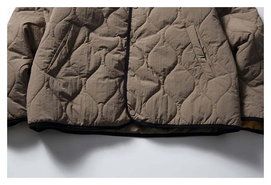 Close-up of the jacket front showing snap buttons, angled pockets, rounded quilting, and black edging.