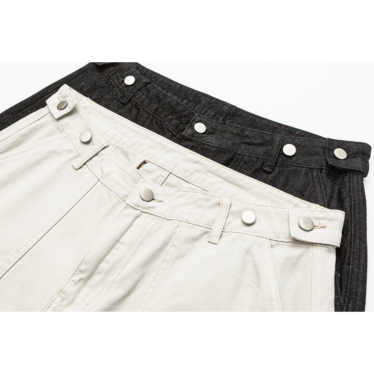 Close-up of off-white and charcoal shorts waistbands with multiple silver snap buttons.