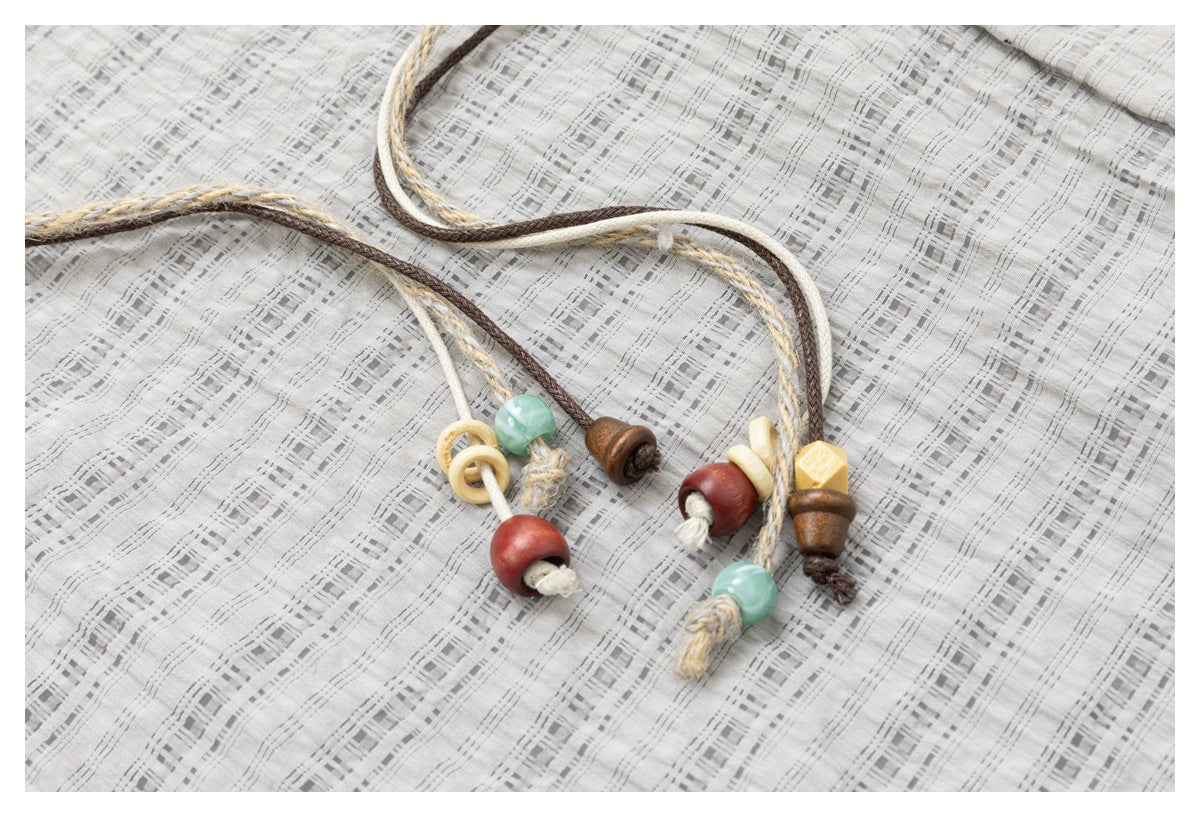 Close-up of the checked fabric and braided drawcord ends with colorful wooden and pale beads.