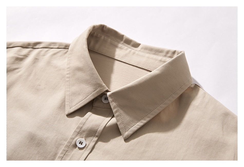 Close-up of a beige button-up shirt collar and upper placket with white buttons.