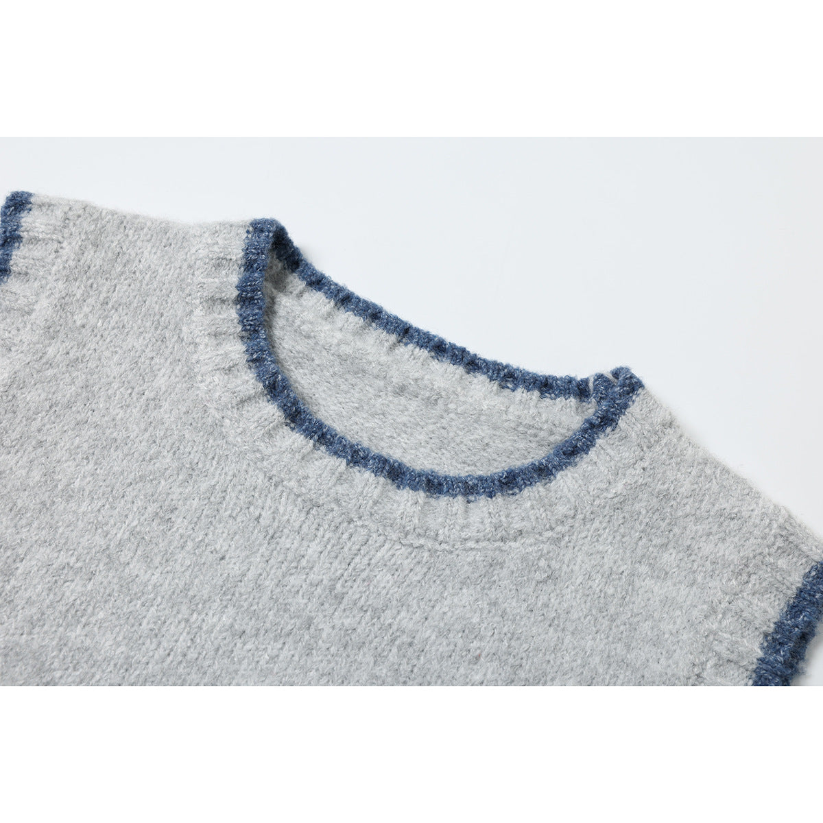 Close-up of a light gray knit top's round neckline with dark blue trim.