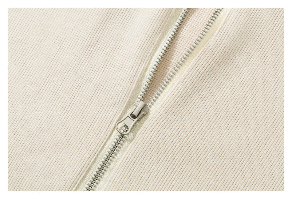 Close-up of the silver front zipper and pull on ivory ribbed fabric.