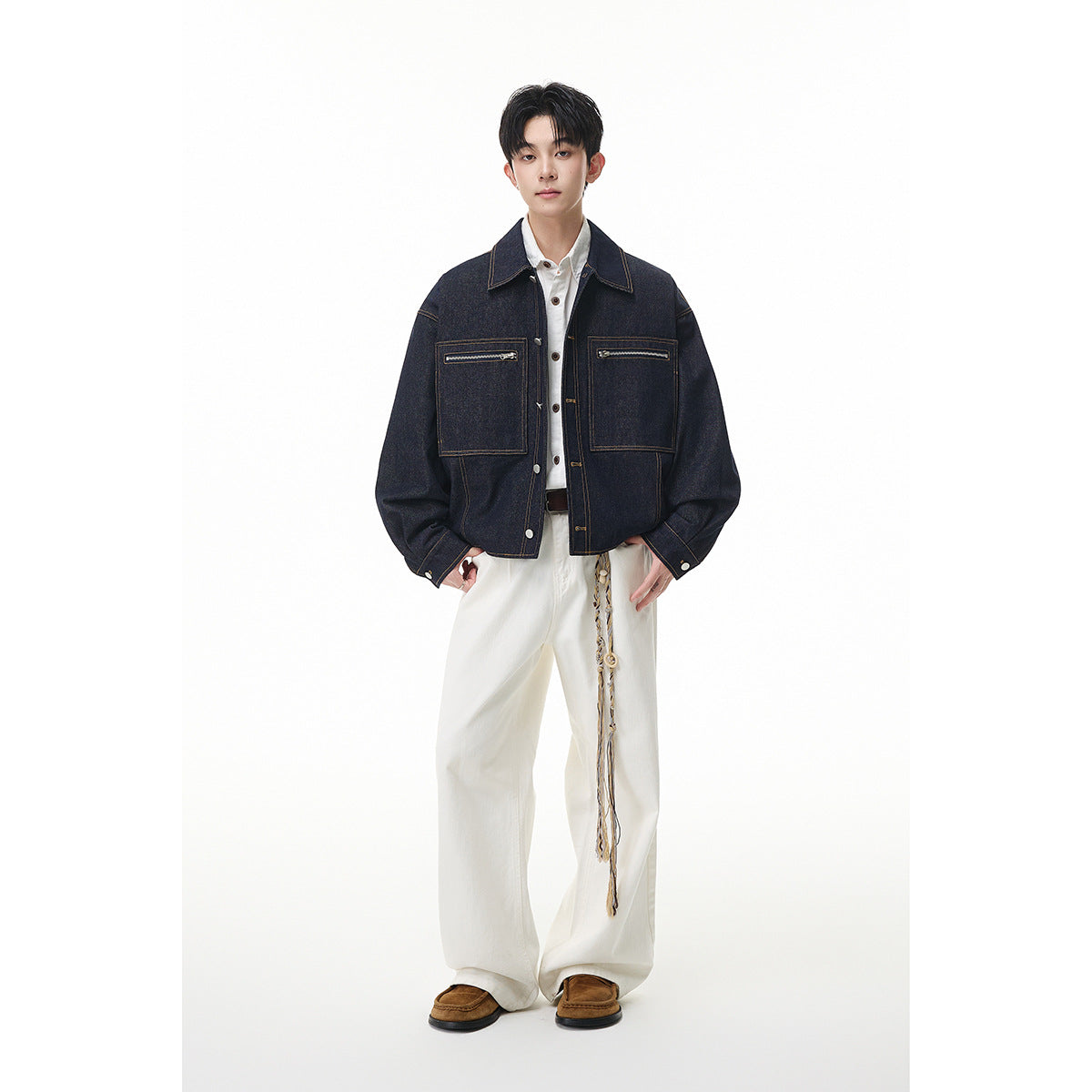 Full-length front view of a model in a dark indigo denim jacket with zip pockets and loose white trousers.