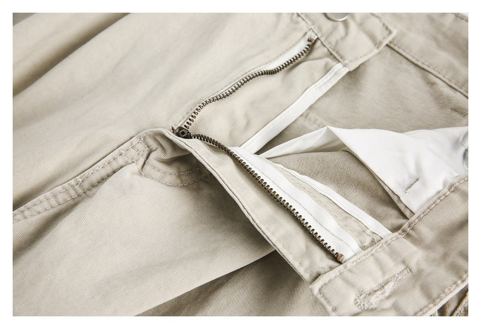Close-up of light beige trousers showing the open metal zipper fly and waistband stitching.