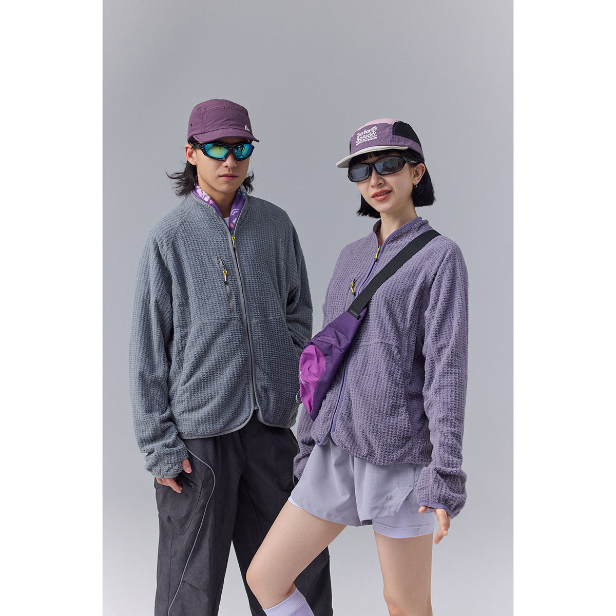Two models wearing textured zip-front jackets, one slate gray and one lavender.