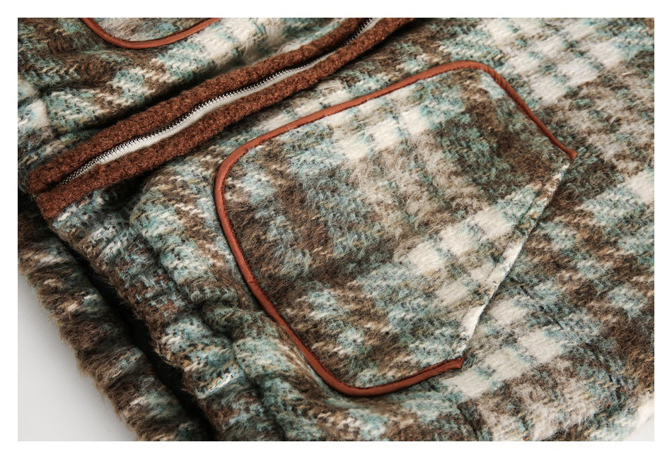Close-up of a brown, cream, and muted teal patterned coat with a rust-trimmed patch pocket and zipper.