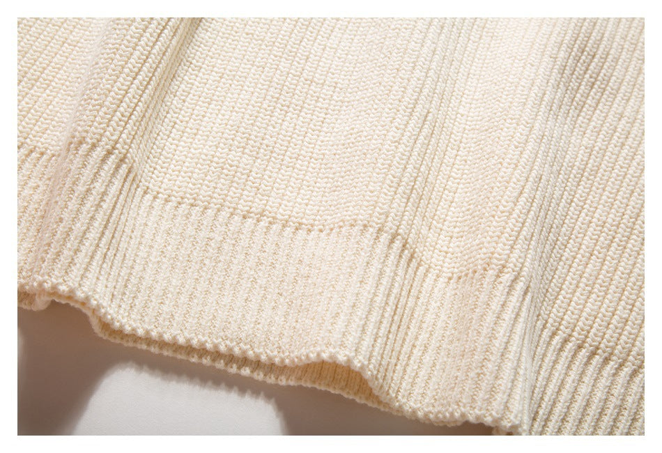 Close-up of an ivory knit garment edge with a textured hem and ribbed section.