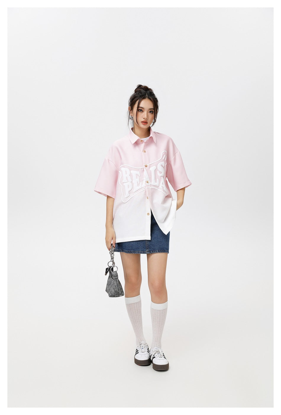 Model wearing a pink-to-white gradient short-sleeve button-up shirt with white puffy lettering, denim skirt and white socks