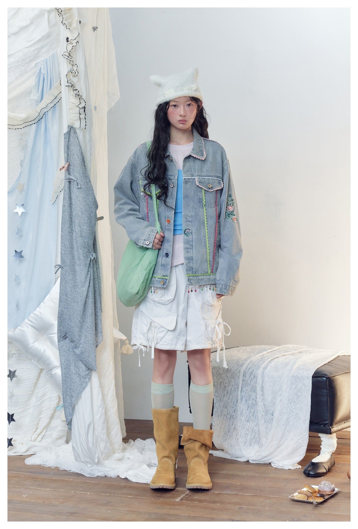 Model wearing the embroidered blue denim jacket open over a blue top and white shorts, front view