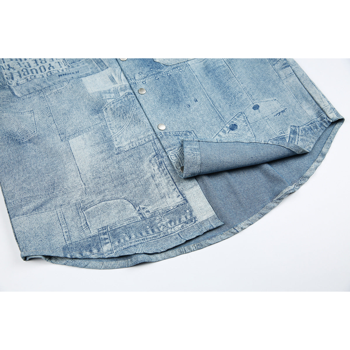 Close-up of the shirt's curved hem and snap-button front, showing the light blue patchwork print.