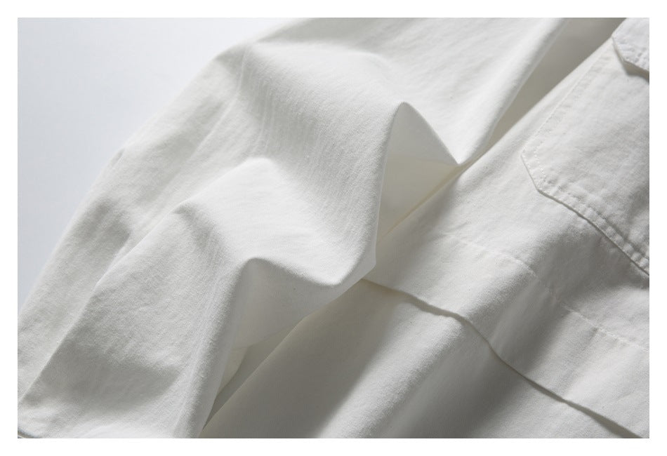 Close-up of white shirt fabric, folded sleeve and front placket.