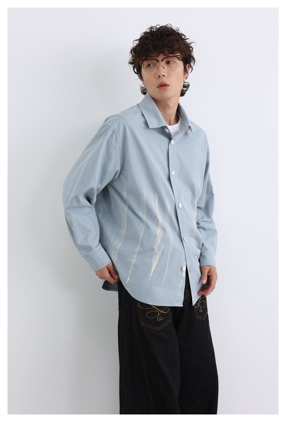 Model wearing a pale blue button-up shirt with light abstract brushstroke graphics.