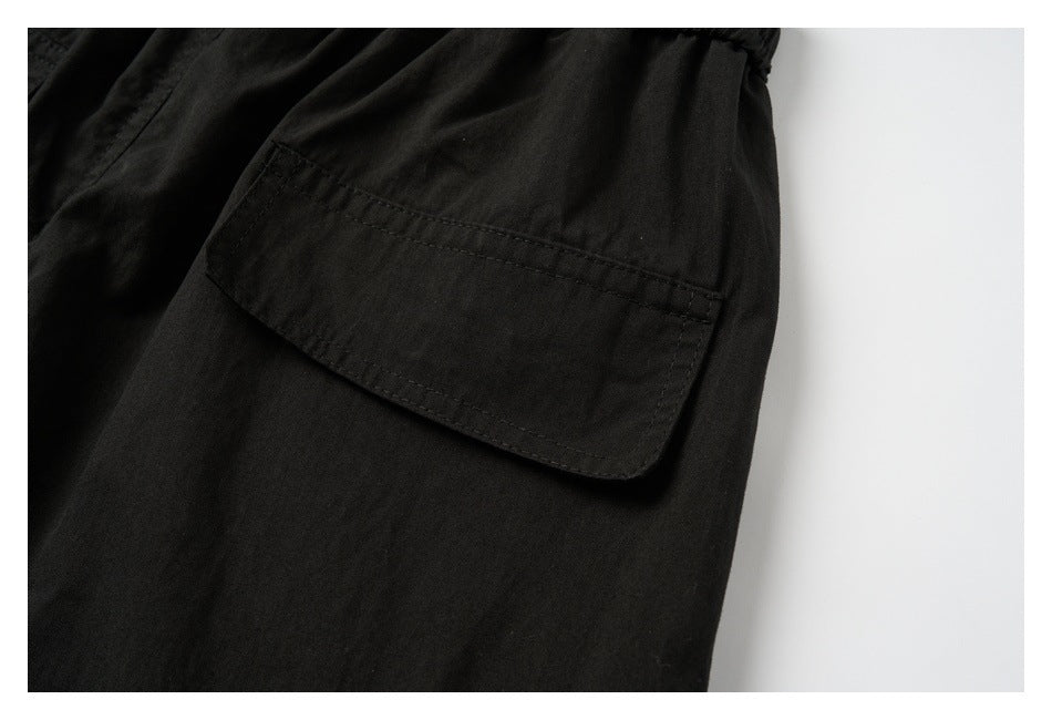 Close-up of a black garment with a large rectangular flap pocket and visible stitching.