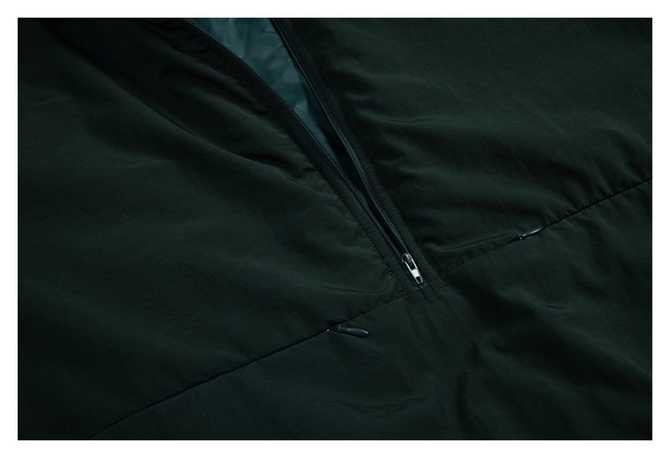 Close-up of the dark green jacket's front zipper and angled seam.