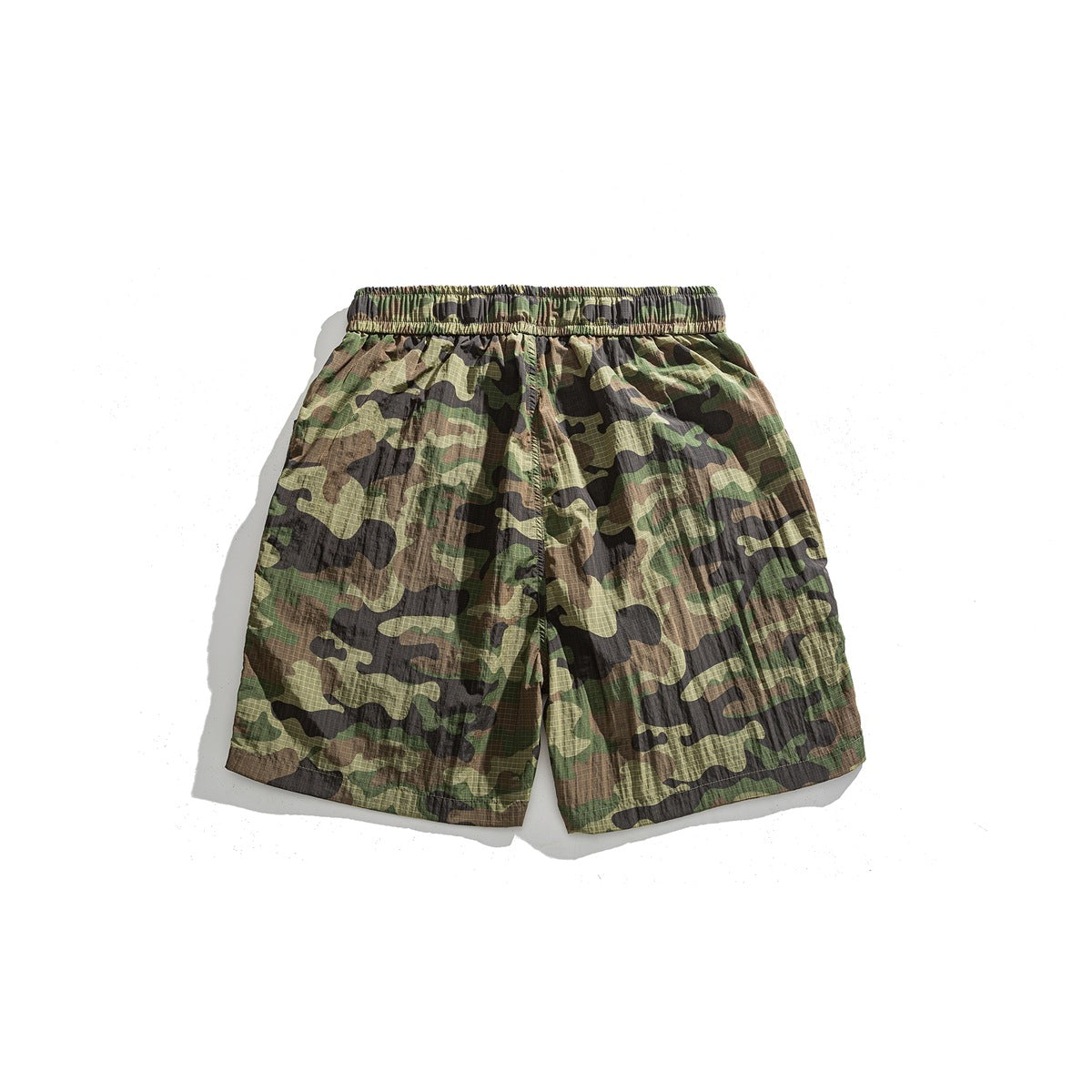 Front view of olive, brown and black camouflage shorts with an elastic waistband, laid flat.