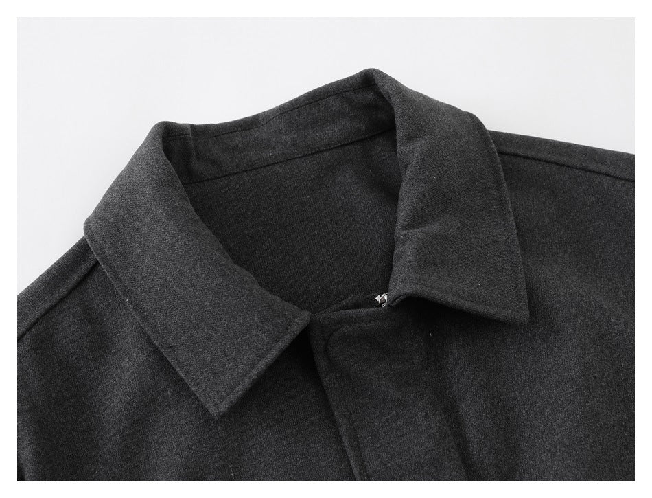 Close-up of a dark charcoal jacket's wide pointed collar and front fastening.