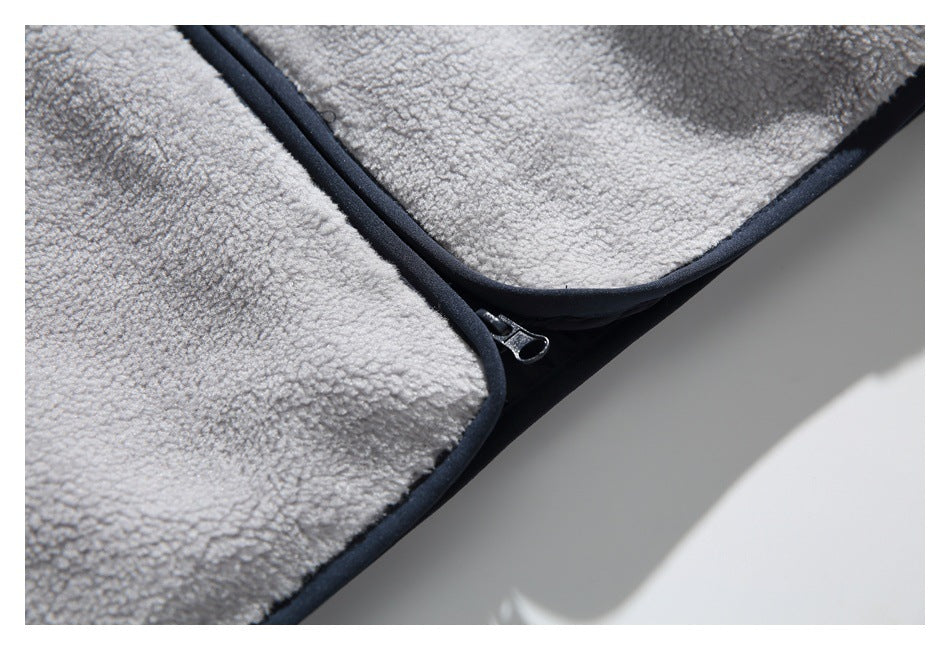 Close-up of the dark zipper pull and edging against the light gray fleece garment.