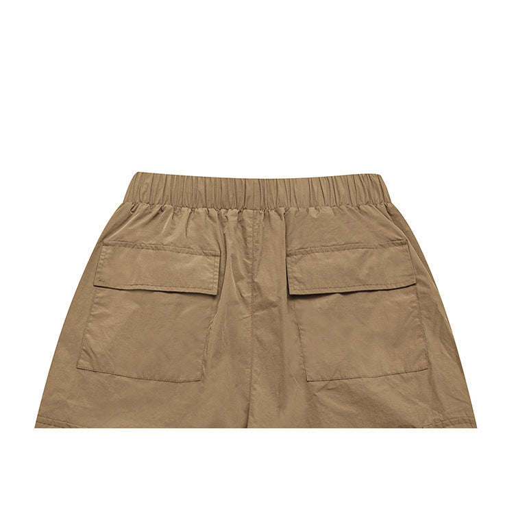 Close view of the back of tan trousers with an elastic waistband and two flap pockets.