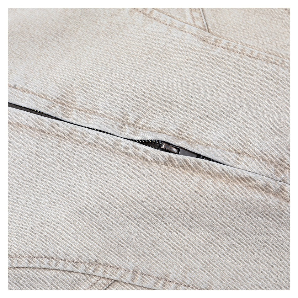 Close-up of a partially exposed dark zipper set into light beige jacket fabric.