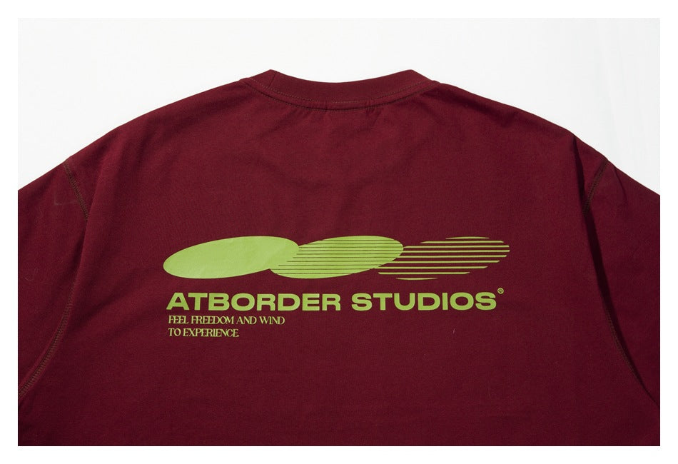 Back view of a burgundy T-shirt laid flat, with a large lime-green graphic and English lettering.