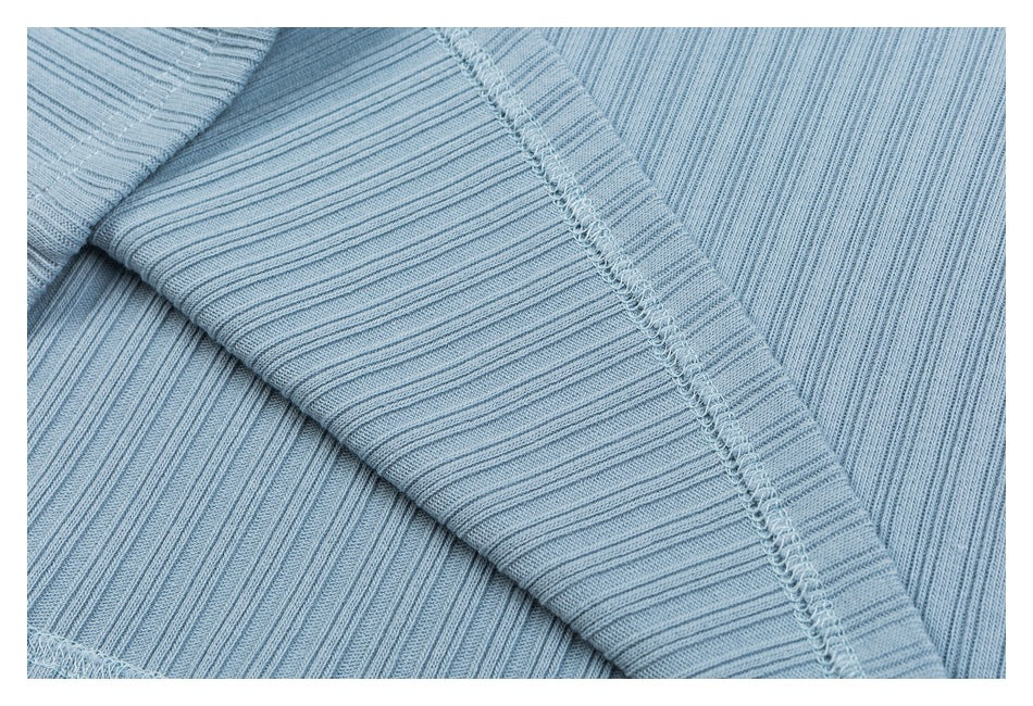 Close-up of light blue rib-knit garment fabric showing a stitched seam and folded edge.