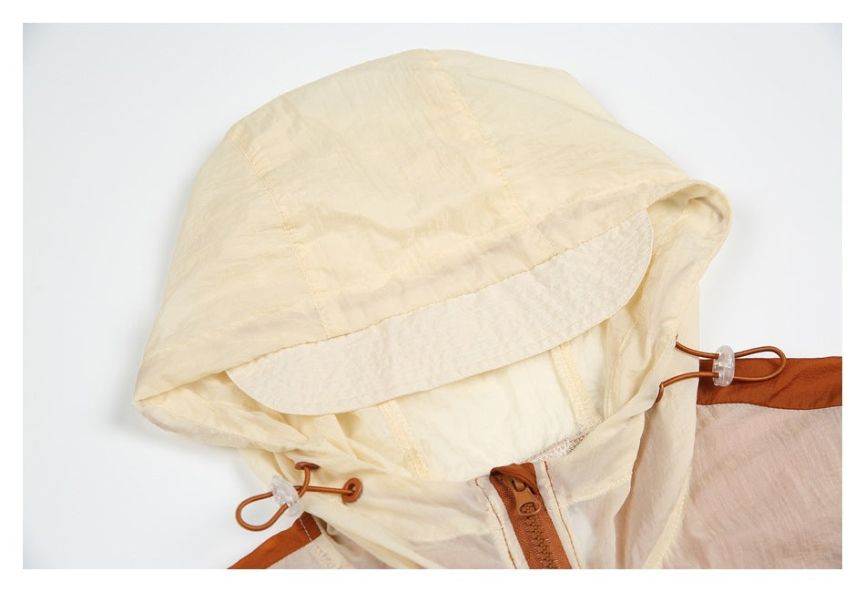 Close-up of a cream hood, drawcord toggles, and zipper on an orange and cream jacket.