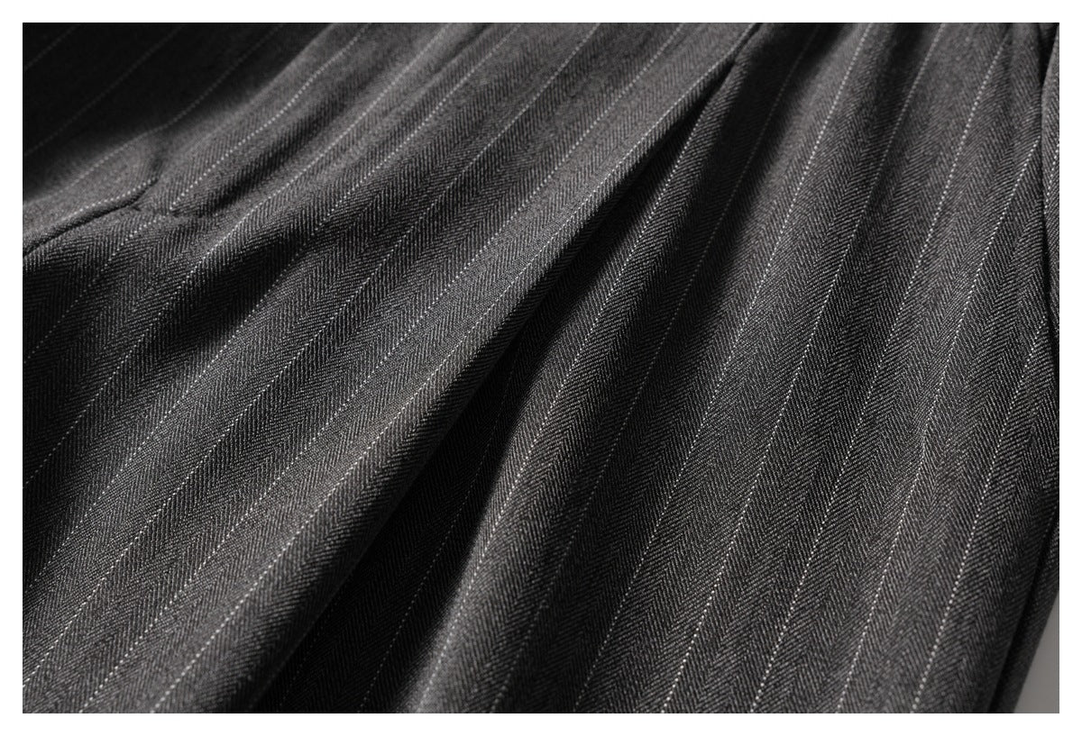 Close-up highlighting the fine light pinstripes and drape of charcoal trousers.