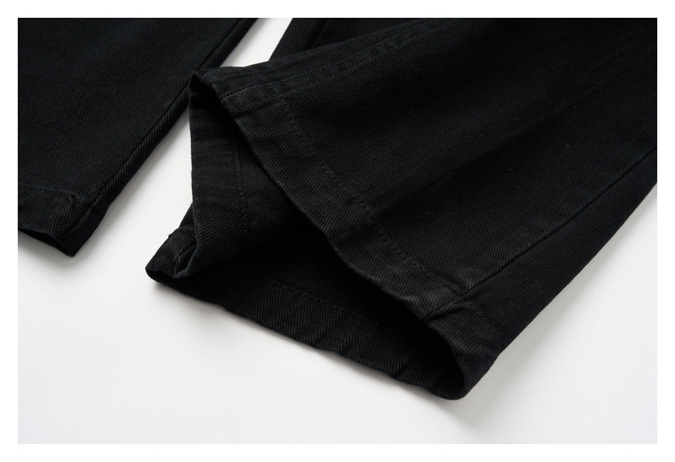 Close-up of a black pant leg hem, showing the folded edge and stitching.