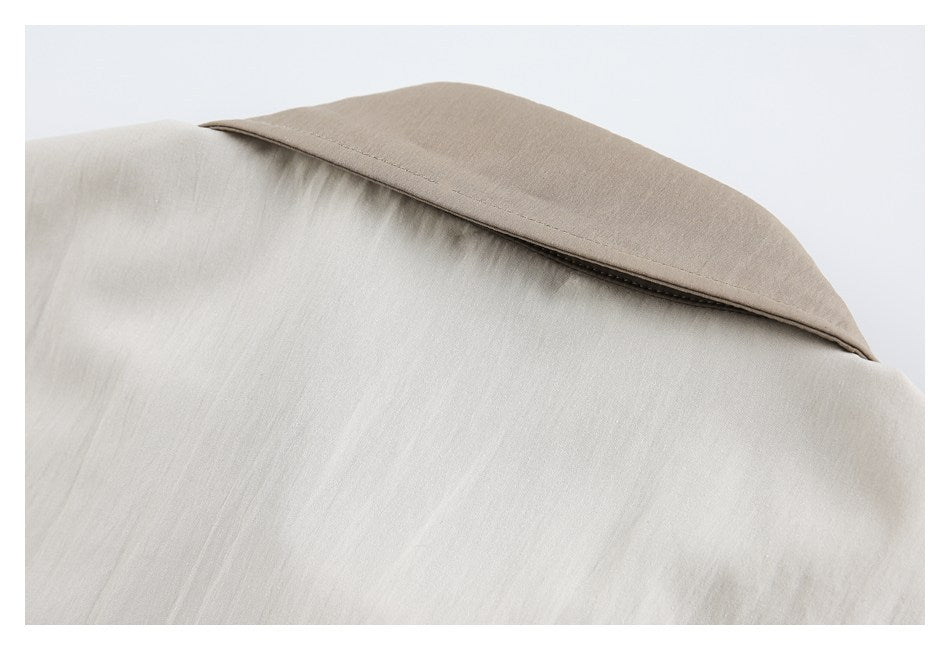 Close-up of a taupe collar against the light beige body of a garment.
