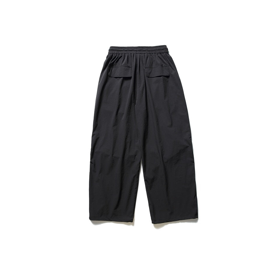 Back view of black wide-leg pants with an elastic waistband and two flap pockets.