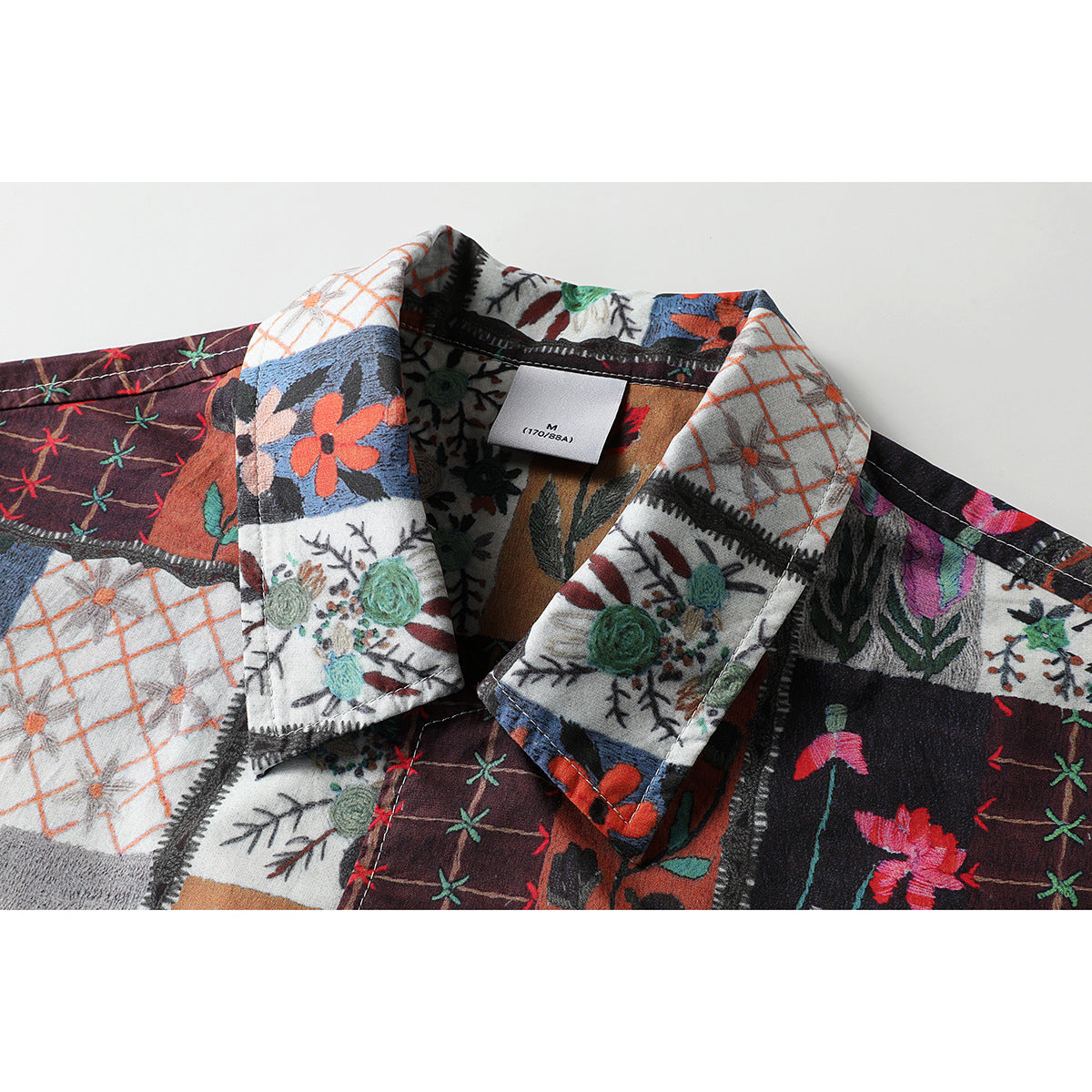 Close-up of a multicolored patchwork shirt collar with floral and geometric panels and a visible M size label.
