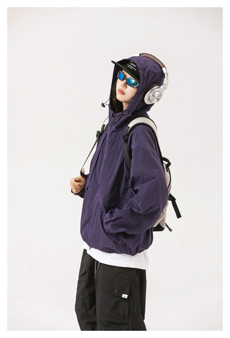 Side view of a model wearing a purple hooded zip jacket with a backpack.