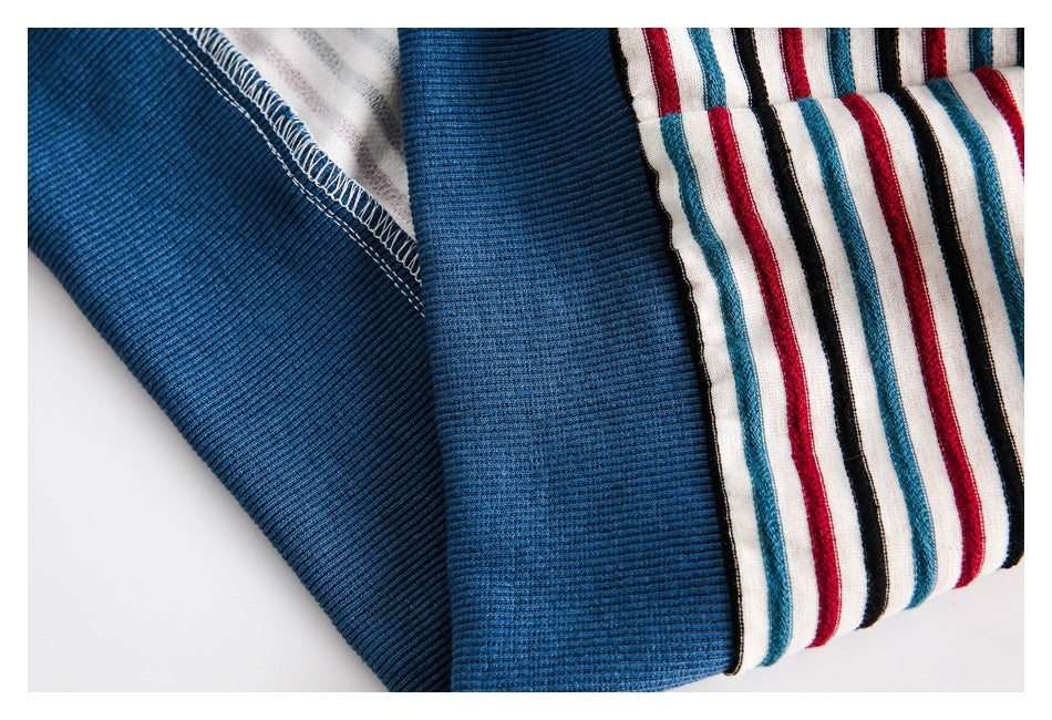 Close-up of folded striped fabric beside a blue ribbed panel and visible overlocked seam.