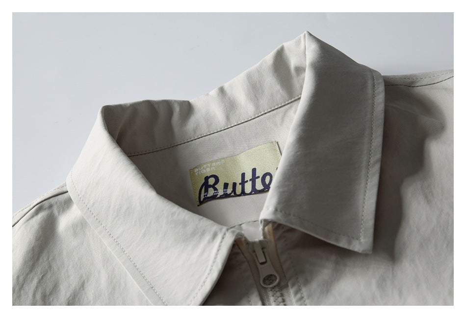 Close-up of a pale gray jacket collar, zipper, and sewn-in brand label.